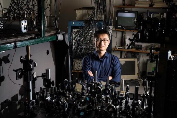 University of Rochester student in a physics lab surrounded by machinery and computers